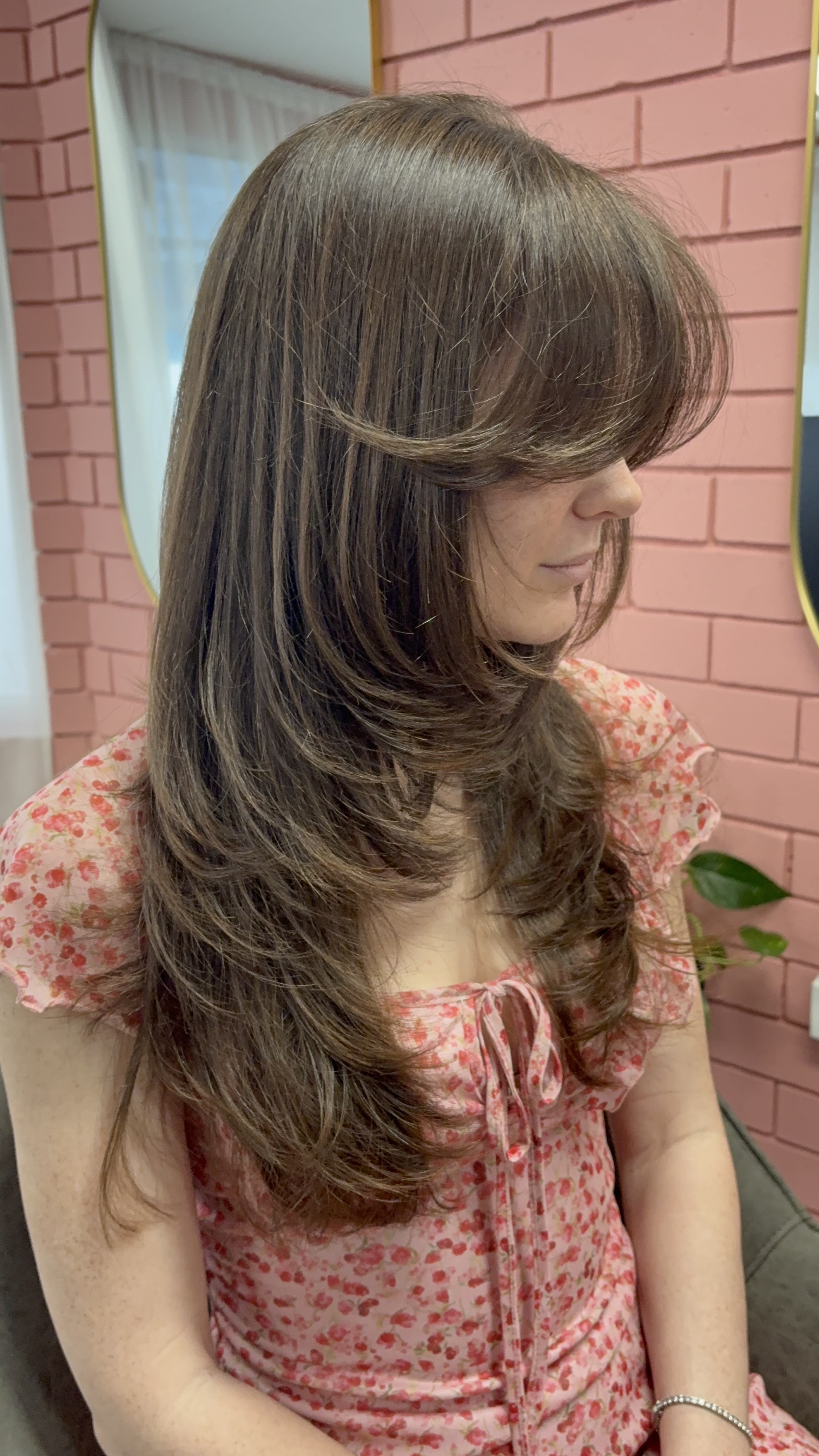 Client with long layers and a soft fringe, relaxed in the salon chair
